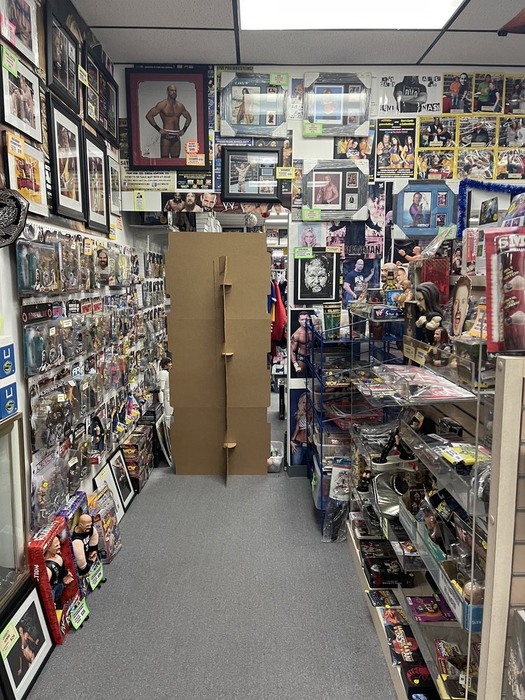 A narrow aisle in Ken's Cards and Collectibles, showing shelves packed tightly with products and limited floor space for customers.