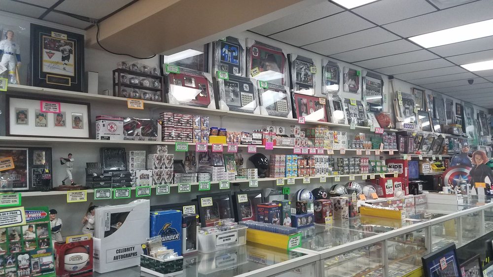 A wide shot of multiple brightly lit glass display cases inside Ken's, filled with high-value sports cards and memorabilia.